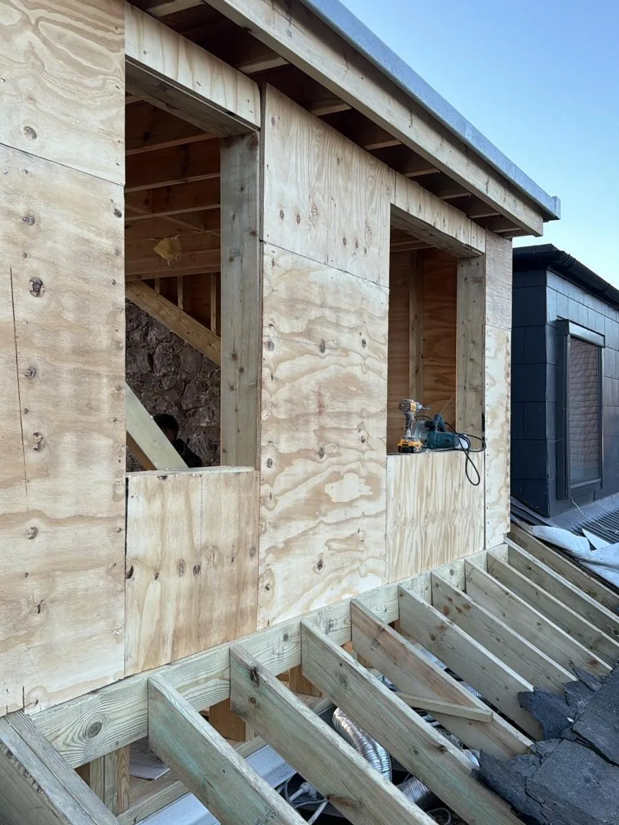 Dormer roof sheathing and exposed timber joists under construction.