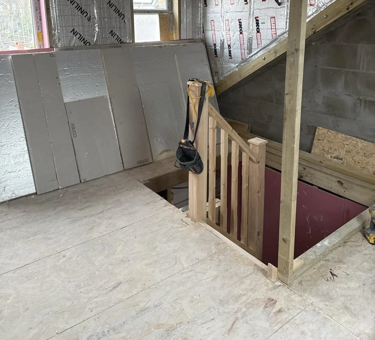 Loft insulation beside timber stairwell framing.